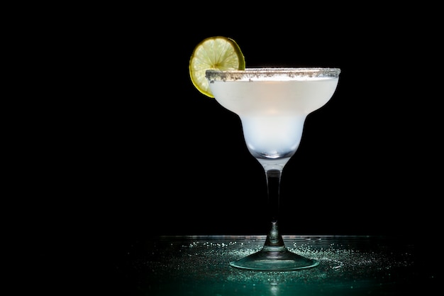 Classic margarita cocktail with lime on a black background