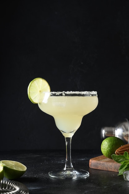 Cocktail classico di margarita con lime e cubetto di ghiaccio su sfondo nero freschezza alcolica estiva freshness