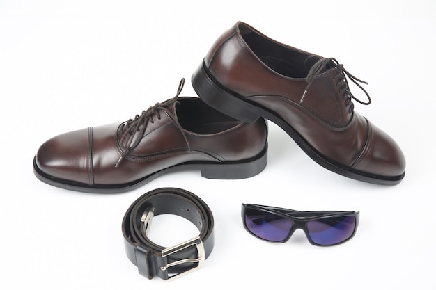 Classic men's shoes, belt and glasses on white