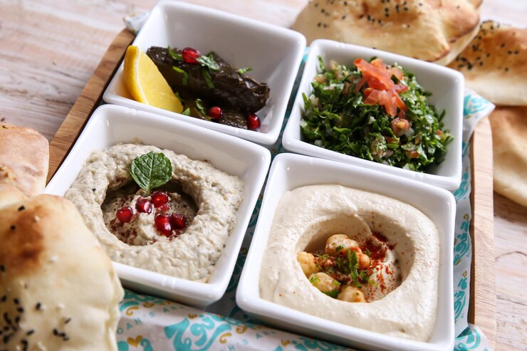 古典的なメッツァの盛り合わせババ Ganoujm トルコ サルサ Labneh Taboula とつるの葉アラビア料理冷たいメッツァの背景の上に分離された皿で提供しています