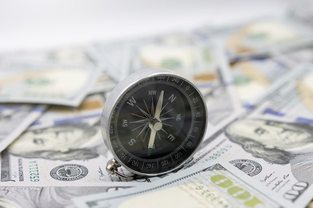 Classic navigational compass on the background of one hundred dollar bills