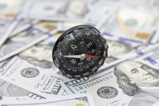 Classic navigational compass on the background of one hundred dollar bills