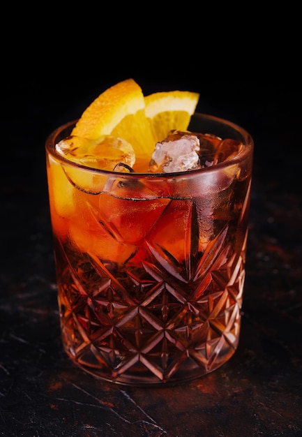 Классический коктейль Негрони с дольками апельсина в стакане