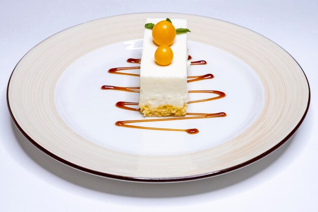 La classica cheesecake newyorkese con physalis e sciroppo su un piatto bianco e uno sfondo delizioso