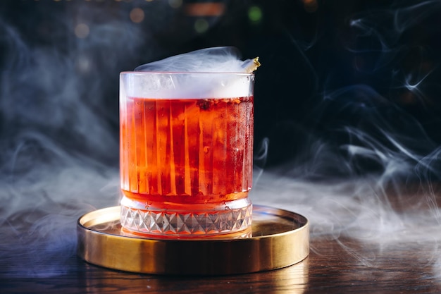 Foto cocktail classico vecchio stile in un bicchiere retrò con fumo