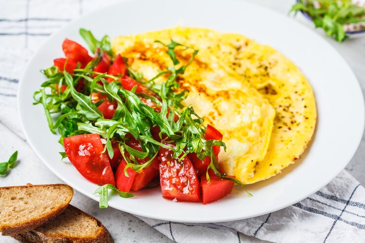 Classic omelet with cheese and tomatoes salad on a white plate.