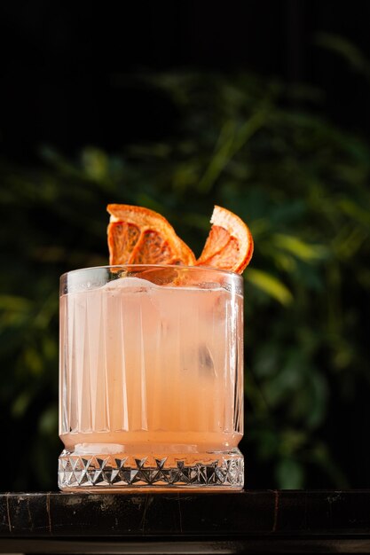 Classic orange cocktail glass on glass table in night club\
restaurant alcohol cocktail drink garnish with orange chips closeup\
modern alcoholic beverage