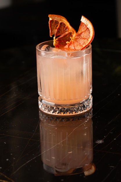 Classic orange cocktail glass on glass table in night club\
restaurant alcohol cocktail drink garnish with orange chips closeup\
modern alcoholic beverage