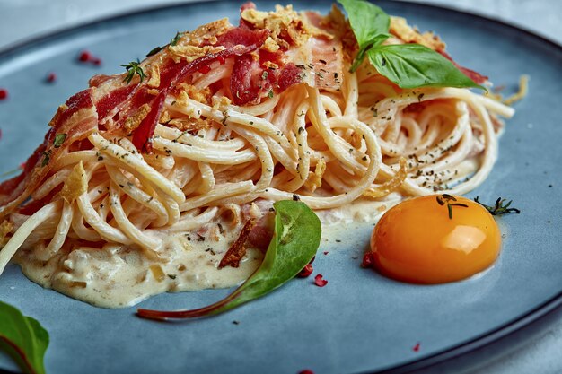 Classic pasta carbonara with yolk on a plate Pasta laid out on a blue plate on a dark background