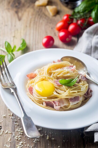 Classic Pasta Carbonara with yolk in a plate on wooden