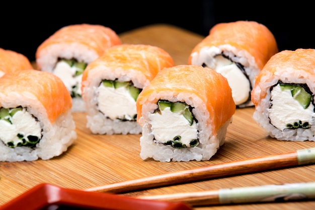 Classic Philadelphia roll with wasabi ginger and soy sauce on a wooden board