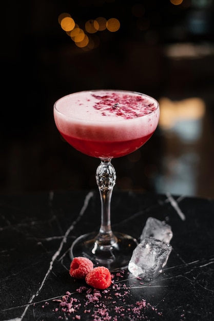 Classic pink cocktail garnished with dried flowers and raspberries