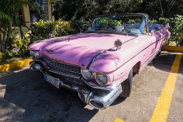 쿠바 바라데로 리조트 타운의 도로에 고전적인 분홍색 복고풍 자동차가 주차되어 있습니다.