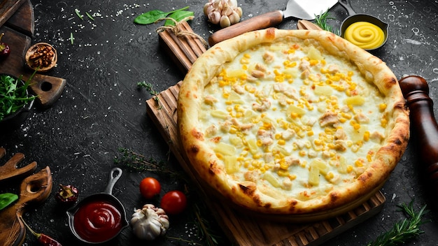 Classic pizza with chicken pineapple and cheese Cheese pizza On a black stone background Top view