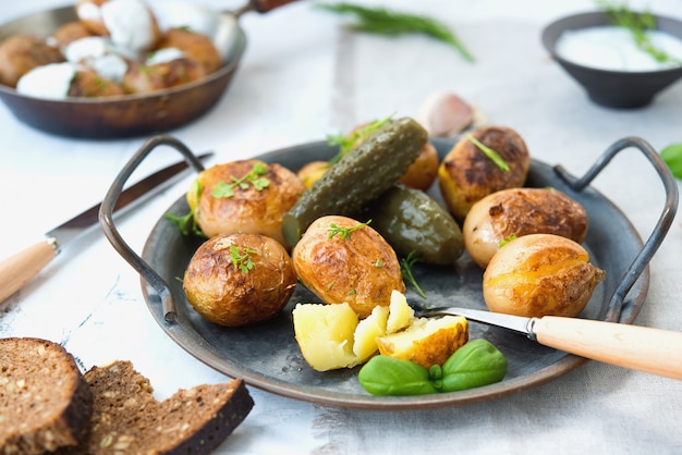 Classic Russian dish baked potatoes with sour cream and herbs and pickles. Horizontal photo.