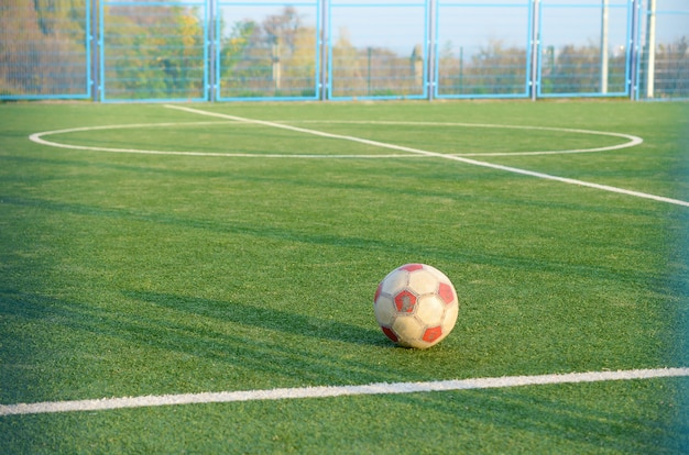 屋外のサッカー緑の芝生フィールドに古典的なサッカーボール。アクティブなスポーツと体育