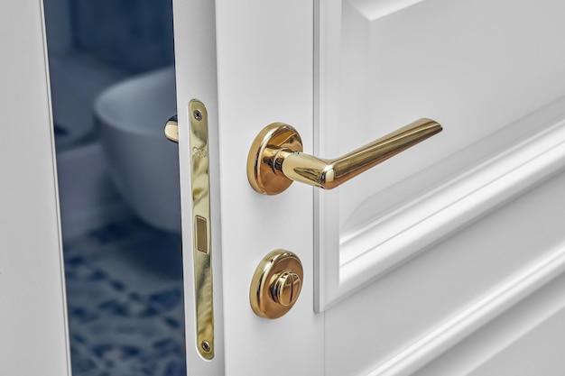 Classic style white door with golden handle Opened white door to the bathroom closeup