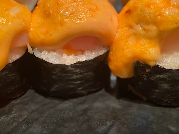 ホタテとおいしいソースを添えた古典的な寿司ロールを限定フォーカスでクローズアップおいしい日本料理またはアジア料理のコンセプト