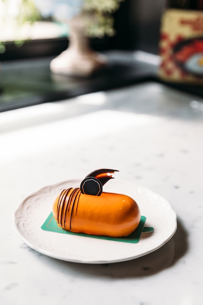 Classic Thai Tea Mousses Cake decorated with chocolate in white plate on marble top table.