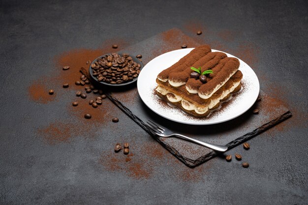 Classic tiramisu dessert on ceramic plate on concrete surface