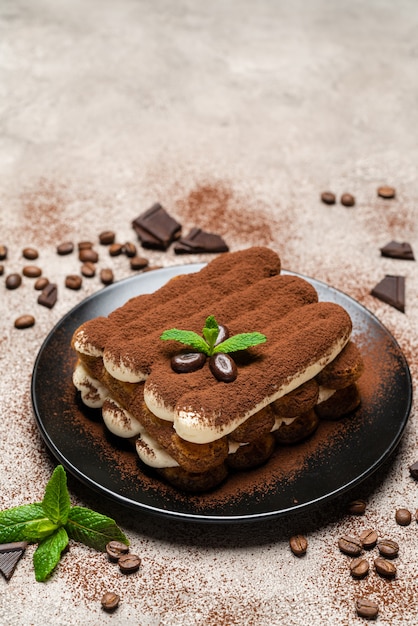 Classic tiramisu dessert on ceramic plate on concrete 