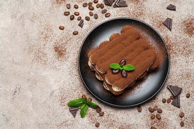 Classic tiramisu dessert on ceramic plate on concrete 