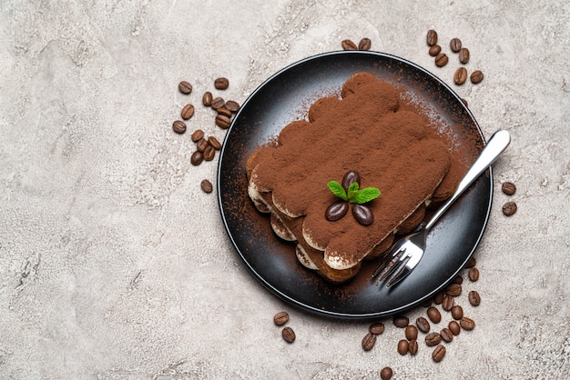 Classic tiramisu dessert on ceramic plate on concrete 