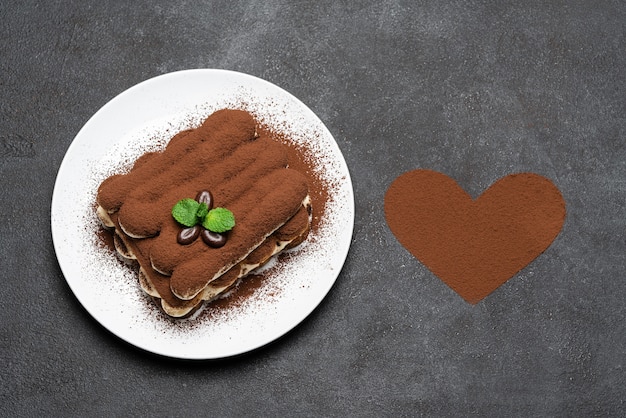 Classic tiramisu dessert on ceramic plate and heart-shaped cocoa powder