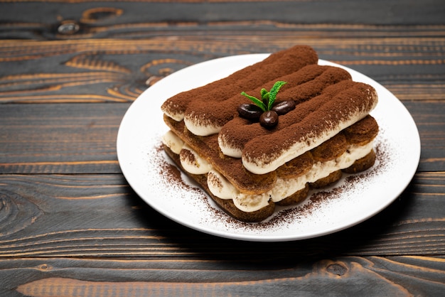 Classic tiramisu dessert on ceramic plate on wooden background