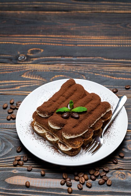 Classic tiramisu dessert on ceramic plate on wooden background