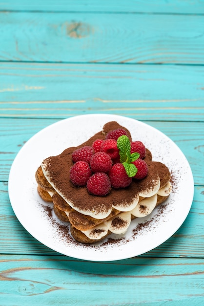 Classic tiramisu dessert with raspberries on blue wooden table