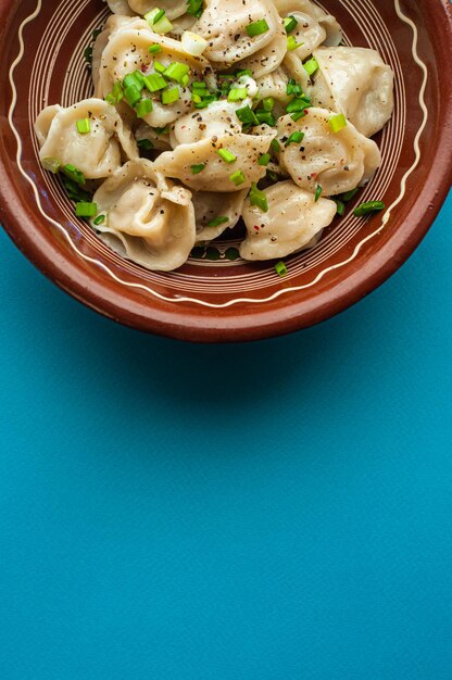 a classic traditional dish of pelmeni dumplings with meat, butter, pepper and greens, food