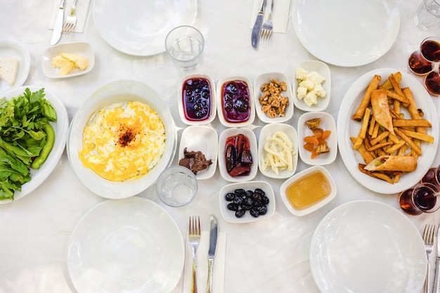 Photo classic turkish breakfast - omelet, cottage cheese, jam, honey, nuts, fried potatoes, herbs, tea.