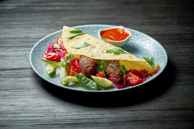 Classic Turkish dish - grilled lula kebab in pita bread with fresh vegetables. Selective focus