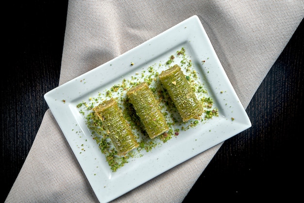 Dolci turchi classici - baklava con miele e pistacchi di pasta sfoglia in un piatto bianco. primo piano, messa a fuoco selettiva