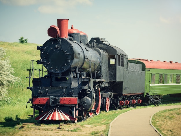 Classic vintage train with a green car on the tracks in summer day.