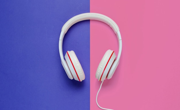 Classic white headphones on blue pink paper background