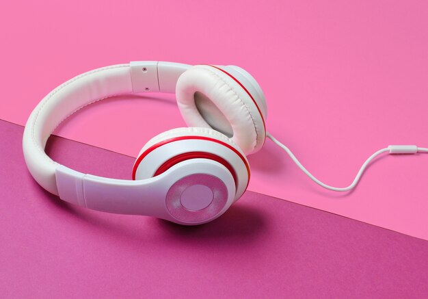 Classic white headphones on pink paper background