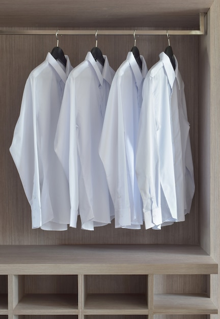 Classic white shirts in warm wooden wardrobe