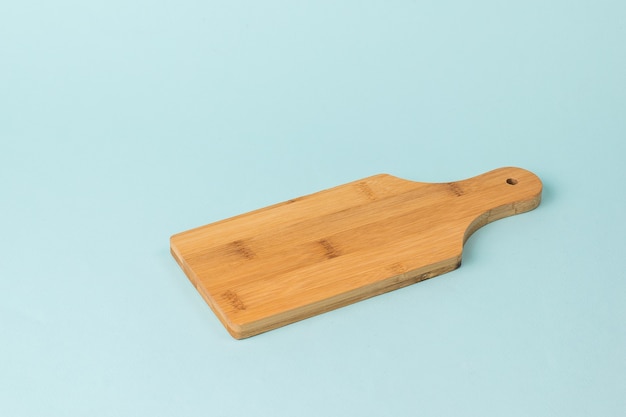 Tagliere di legno classico sull'azzurro. accessori per la cucina.