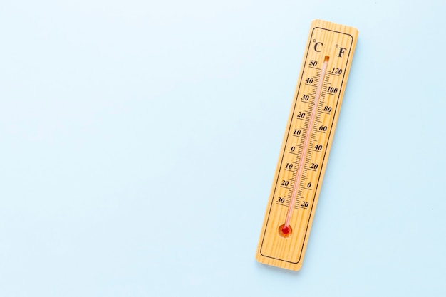 A classic wooden thermometer on blue background doesn't show any temperature. Copy space