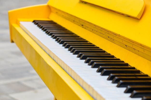 Classic yellow piano on the street close up.