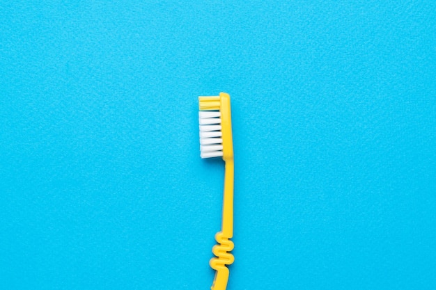 Classic yellow toothbrush on a light blue background Flat lay