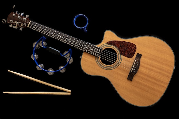 검은 배경에 클래식 어쿠스틱 기타, 드럼 스틱, 탬버린, 커피 컵, 위쪽 전망, 음악적 창의성 개념.
