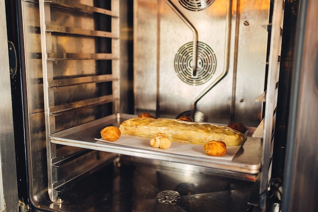 Strudel di mele classico su teglia di metallo nel forno, nessuno. pasticceria dolce, preparazione di dolci fatti in casa