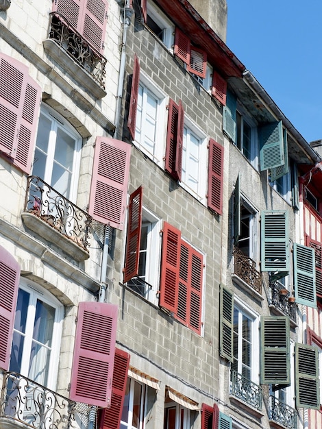 Classical colourful facades in Bayonne french part of Basque Country France Different windows and balconies with shutters of faded colours Vertical photo