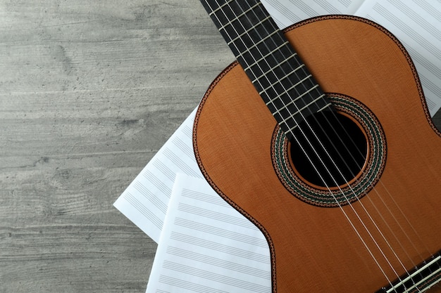 Classical guitar and music sheets on gray textured table