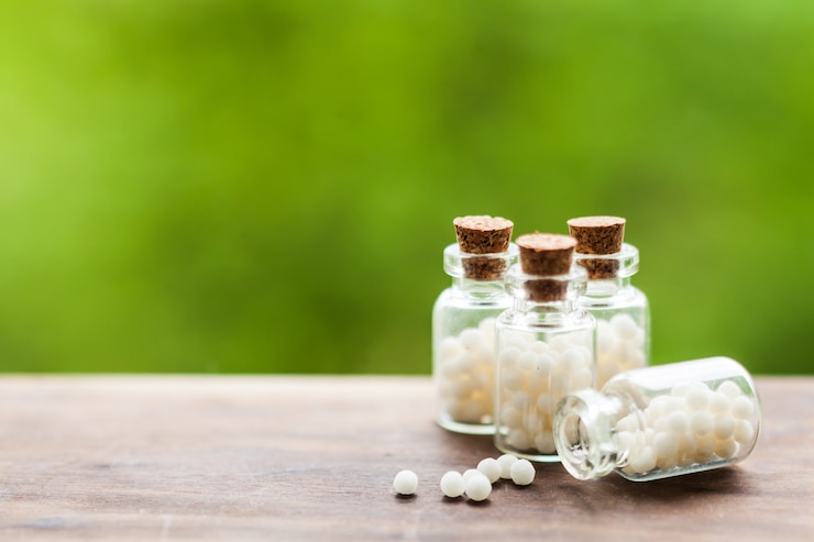 Photo classical homeopathy globules in vintage bottles and nature leaves