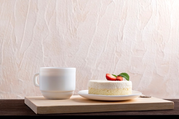 Classical New York Cheesecake with strawberries and cup of coffee or tea.