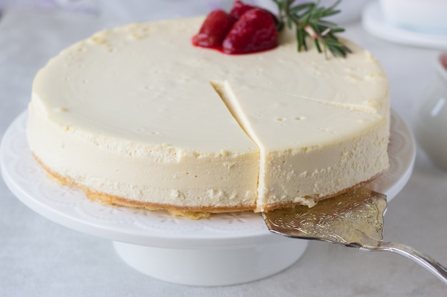 Photo classical new york cheesecake with strawberry sauce and rosemary